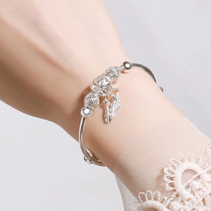 Close-up of a silver dreamcatcher feather bracelet on a female model with lace sleeve