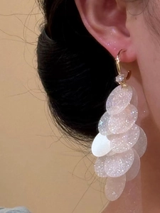 Close-up of cascading white iridescent sequins and gold metal rings on a C-shaped earring