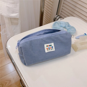 Close-up of light blue corduroy pouch with a floral BEST patch and metal zipper closure