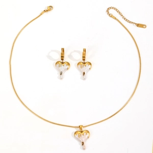 Golden heart necklace and earring set with white enamel drip texture on white background