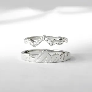 Macro detail of mountain-themed rings with micro-paved crystals and 3D textured relief