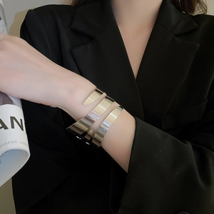Polished silver geometric multi-layer crossover bangle worn on a model's wrist