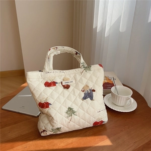 Detailed quilted pattern on a beige tote bag featuring cute bears and rabbit prints