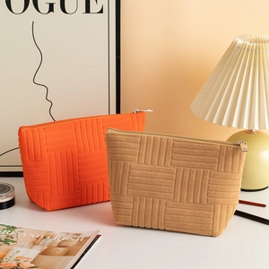 Detail of orange and khaki terry cloth makeup bags with textured checkered pattern