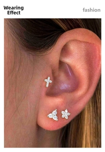 Detailed close-up of G23 titanium ear studs featuring zircon cross and flower designs