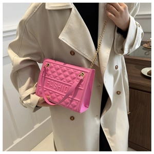 Pink embossed handbag with metal chain strap carried by model in beige trench coat
