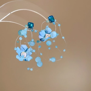 Macro view of blue fabric flower earrings with long tassels and crystal bead details