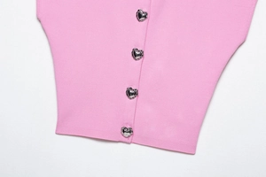 Dettaglio di un top in maglia rosa con bottoni metallici argentati a forma di cuore