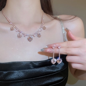 Close-up of a model wearing a pink zircon heart pendant necklace and tassel earrings