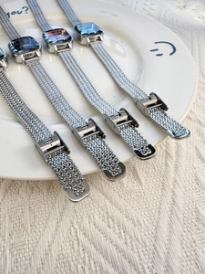 Silver square watches with mesh metal straps and colorful dials on a white plate