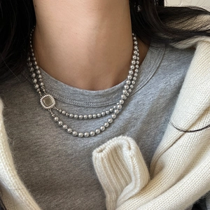 Close-up of double-layer grey pearl necklace with square gemstone buckle on model