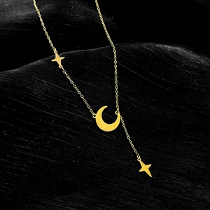 Detail of gold star and crescent moon pendants on a titanium steel Y-shaped necklace