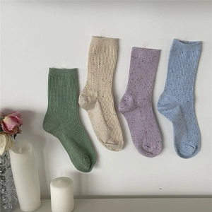 Detail of four colorful ribbed cotton socks with confetti specks on a white background