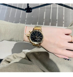 Detail of the TICTOC golden metal watch band and black multifunctional dial on wrist