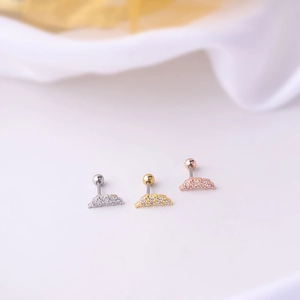 Macro shot of wing-shaped stainless steel earrings in silver, gold, and rose gold finishes