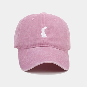Close-up of white rabbit embroidery on a vintage washed pink cotton baseball cap detail