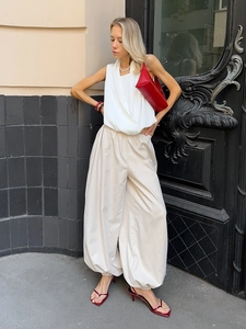 Detail of white wrap top and beige pleated wide-leg trousers with red accessories