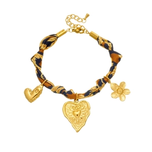 Bracciale in tessuto leopardato con ciondoli a cuore e fiori dorati su sfondo bianco