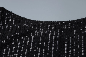 Macro shot of shimmering black sequin fabric texture on a long backless evening dress