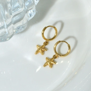 Close-up of 14K gold stainless steel earrings with textured starfish pendants