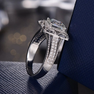 Luxurious silver ring with rectangular center stone and pavé diamonds on blue box
