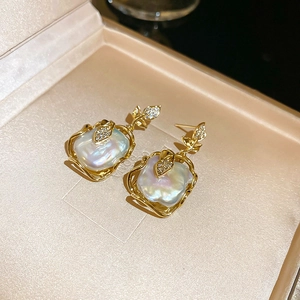 Détail de boucles d'oreilles feuille avec perle baroque et diamants en écrin