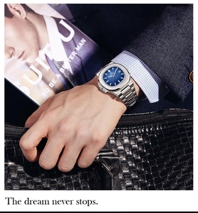 Close-up of a luxury men's steel watch with a blue dial worn with a formal suit