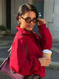 Detailansicht eines roten Damen-Sweatshirts mit halbem Reißverschluss und einer lila Handtasche