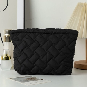 Close-up of black quilted makeup bag with diamond texture in a cozy home setting