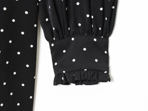 Dettaglio di polsini elastici a balze su abito in chiffon nero a pois eleganti