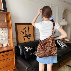 Lifestyle shot showing a trendy leopard print canvas crossbody bag on a model's shoulder