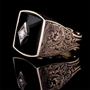 Macro shot of vintage gold men's ring featuring black gemstone and ornate carving details