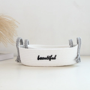 Detail of two white cotton rope baskets featuring beautiful embroidery and gray handles