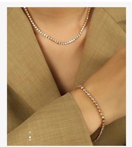 Gros plan d'un ensemble collier et bracelet tennis en or avec zircons sur un mannequin