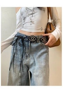 Detail of punk leather belt featuring silver studs and long leather tassels on denim