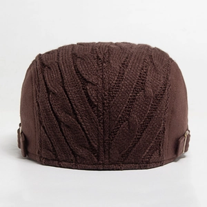 Close-up of thick knitted dark brown beret with cable knit pattern and metal buckle detail