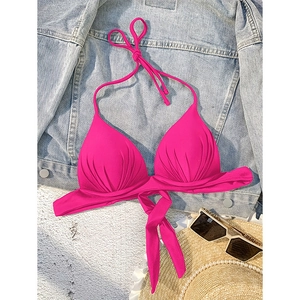 Hot pink halter neck tie-front bikini top with textured fabric on a beach setup