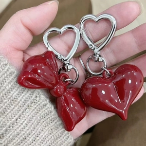 Detail shot of two dark red acrylic bow and heart charms for bags and keychains