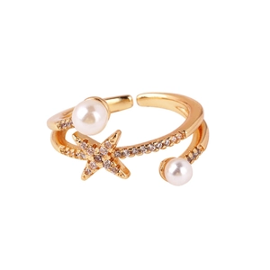 Detail showing two white pearls and a sparkling star-shaped charm on a gold-plated ring