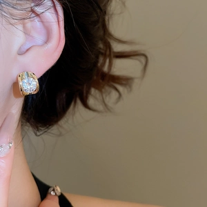 Close-up of 18k gold plated C-shaped earring with a large sparkling zircon on ear