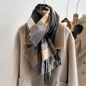 Detail of plaid cashmere-feel scarf with fringe edges styled on a beige wool coat