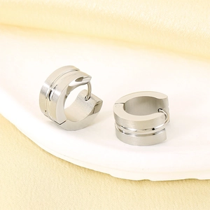 Macro detail of silver C-shaped huggie earrings with brushed and polished metal textures