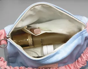 Macro view of blue corduroy cosmetic bag with pink handle and large capacity storage