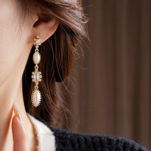 Close-up of vintage gold tassel earrings with oval white pearls and zircon on a model