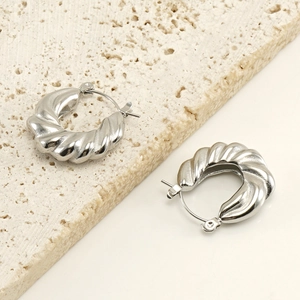 Gros plan de boucles d'oreilles croissant argentées sur pierre de travertin