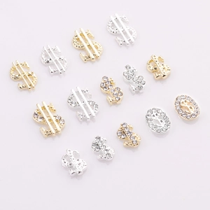 Detailed macro view of gold and silver dollar sign nail art charms with crystal rhinestones