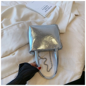 Fashionable silver pleated leather handbag held by a model in a minimal setting