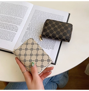 Close-up of compact leather card holders with classic chain print and gold zippers