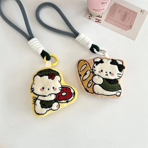 Detailed view of plush cat charms featuring donut and baguette embroidery designs