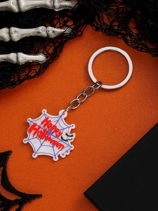 Detail of a white spider web keychain with red Happy Halloween text on orange background